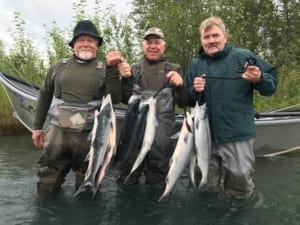 Proud fly fisherman hoist their most recent bounty from the shores of the Kenai River.