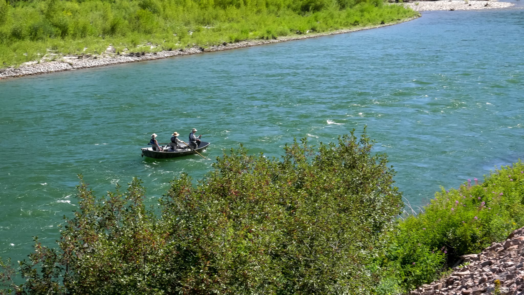 A towering view of three anglers using a drift boat in Alaska.